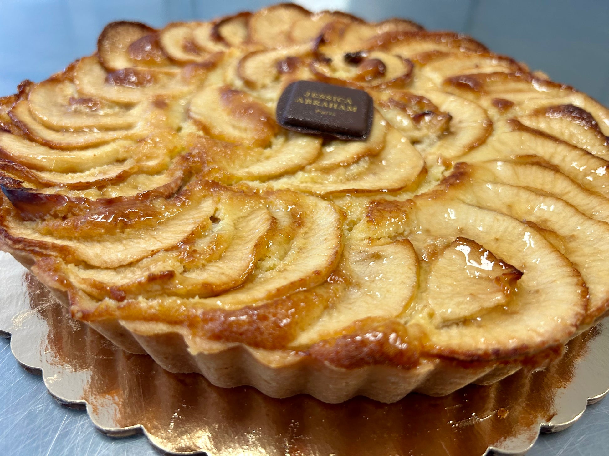 Apple tart with a 'jessica abraham' brand label on a blue surface