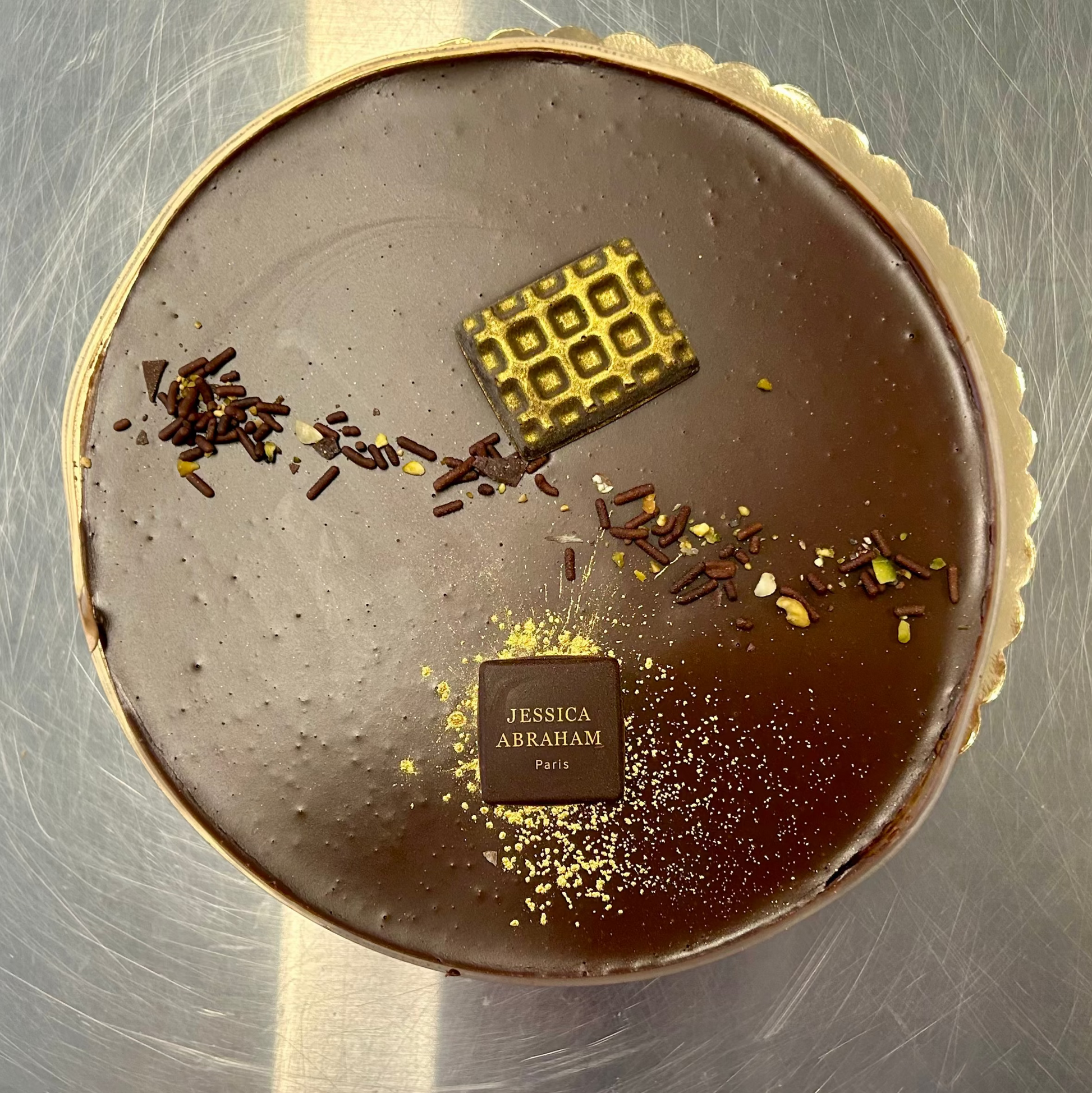 Chocolate dessert with 'jessica abraham'  decorative elements on a metallic surface