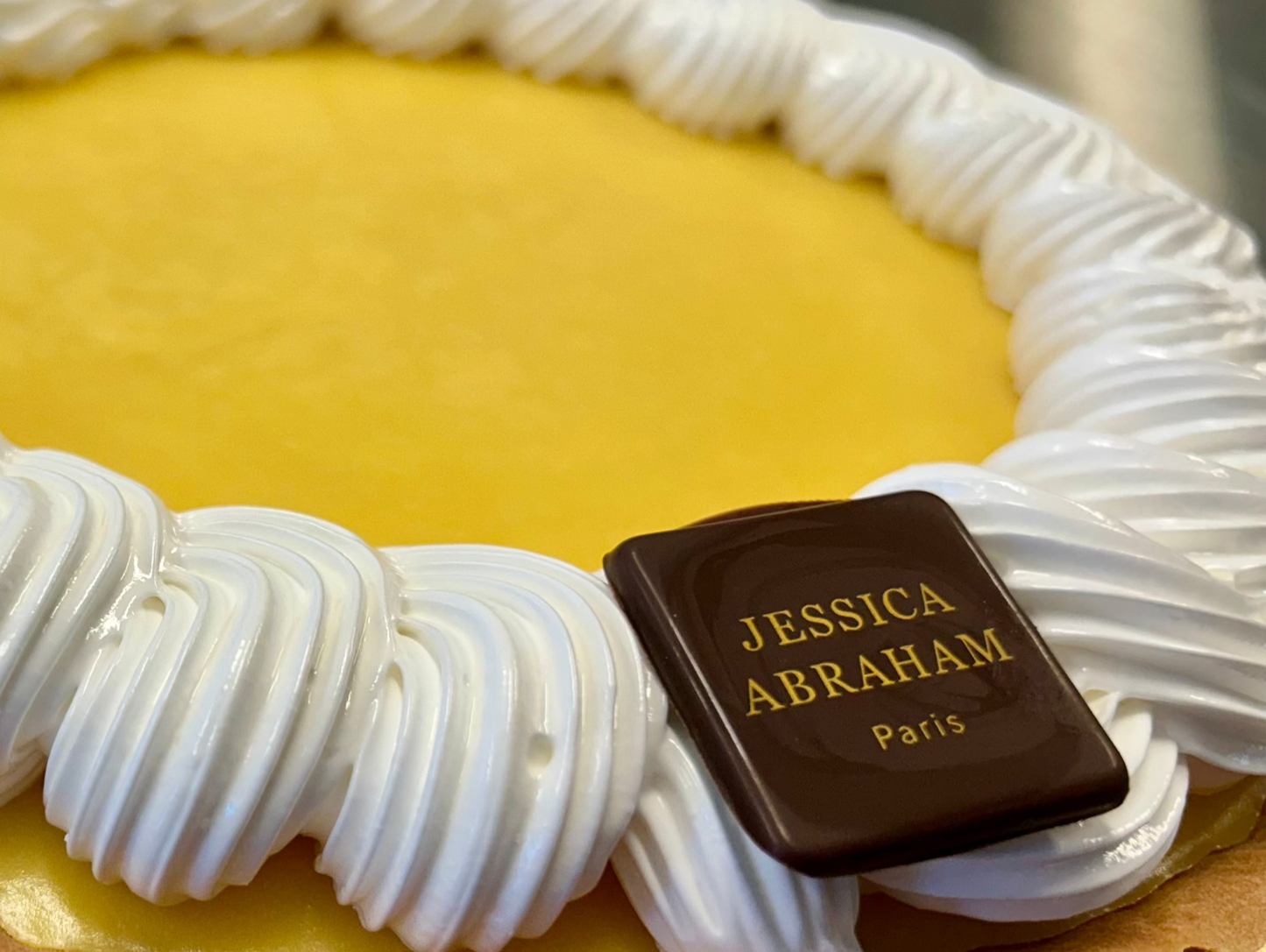 French lemon meringue tarte with 'jessica abraham' chocolate nameplate on a metallic surface 